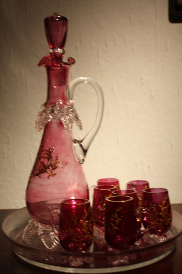 A vintage 1900 Bohemian pink glass liquor pitcher with 7 glasses on a tray